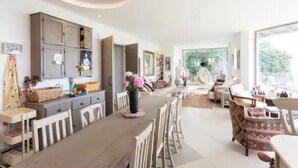 Un vaste espace de vie comprenant une table à manger, des chaises et une grande fenêtre offrant une vue sur l’extérieur.