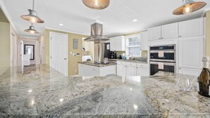 A kitchen with granite countertops, stainless steel appliances, and pendant lighting.