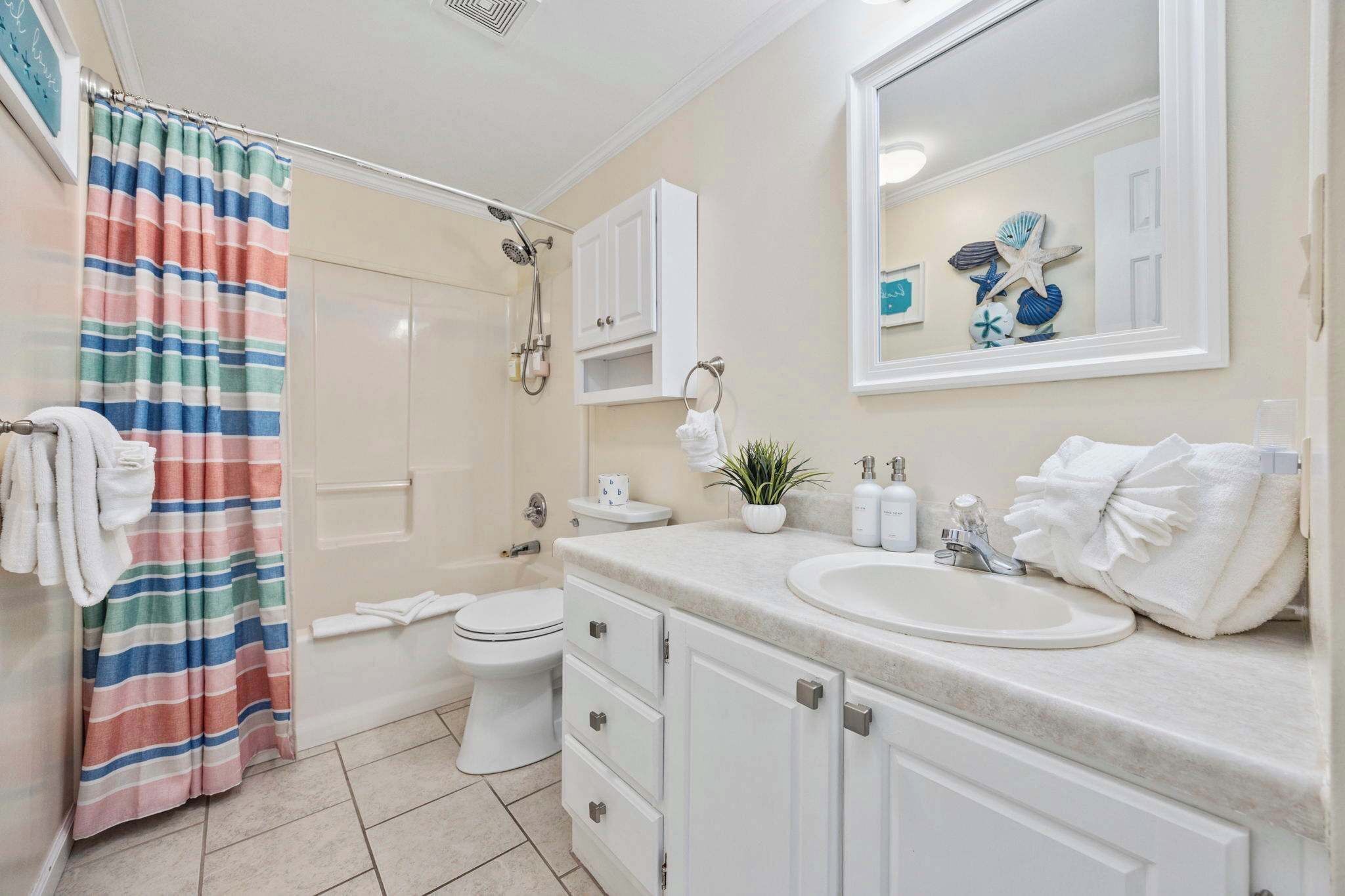 A bathroom with a shower, toilet, sink, and cabinets.