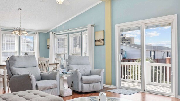 A spacious living room with a large sliding glass door to the outside, a ceiling fan, and a dining area with a table and chairs.