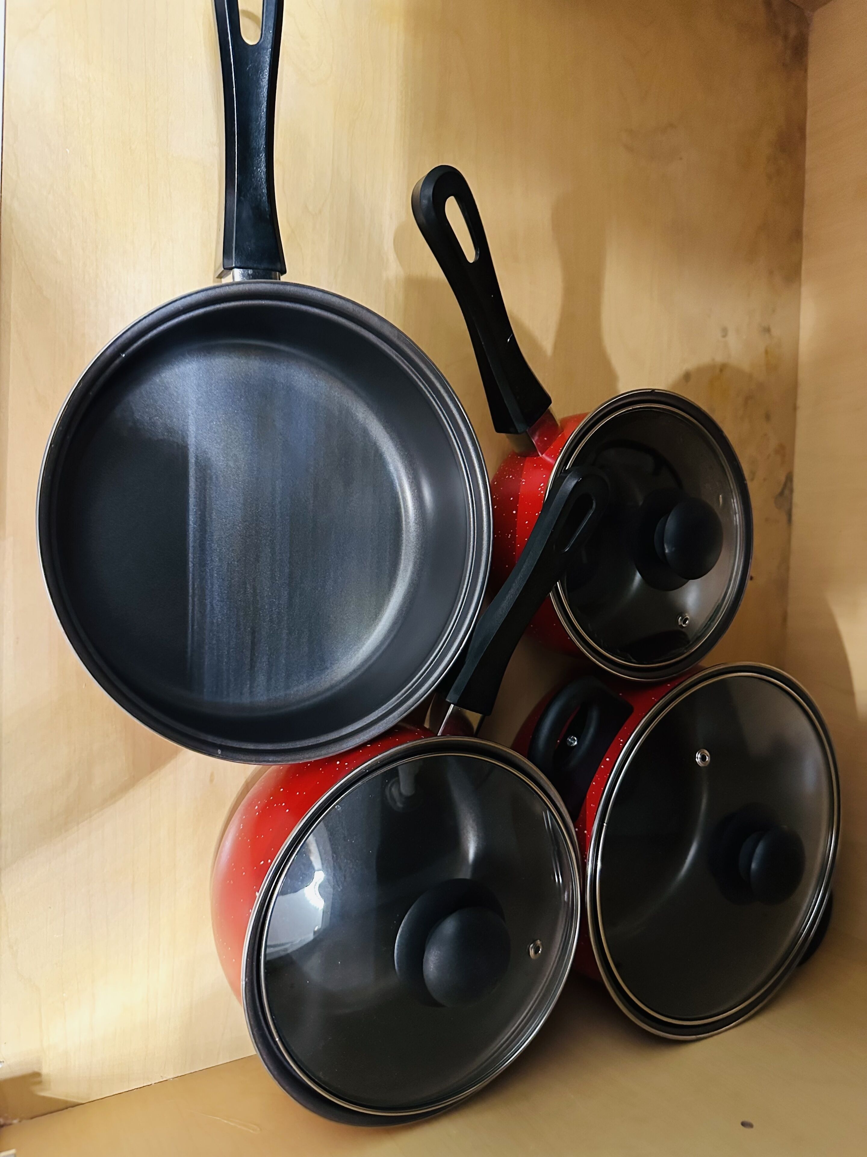 A set of cookware including a frying pan and three pots, placed on a wooden surface.