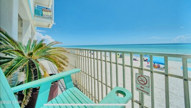 A balcony with a view of a beach, a palm tree, and a 'No Smoking' sign. - Newly renovated studio on the beach # 207 (Panama City Beach)