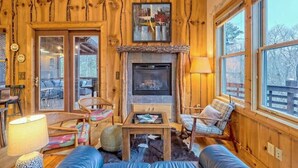Ein gemütliches Blockhaus-Interieur mit Kamin, Holzwänden und großen Fenstern.