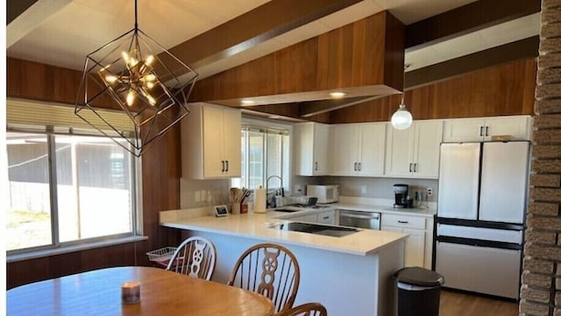 Une cuisine moderne avec des meubles en bois, un îlot central et un coin repas comprenant une table et des chaises en bois.