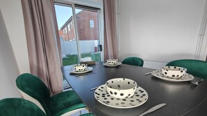 A dining table with four white bowls with black polka dots, a knife, and a spoon. The table is surrounded by green upholstered chairs. - 3 Bed House - Sleeps 7 - Garden - Parking - Wifi (Birmingham)