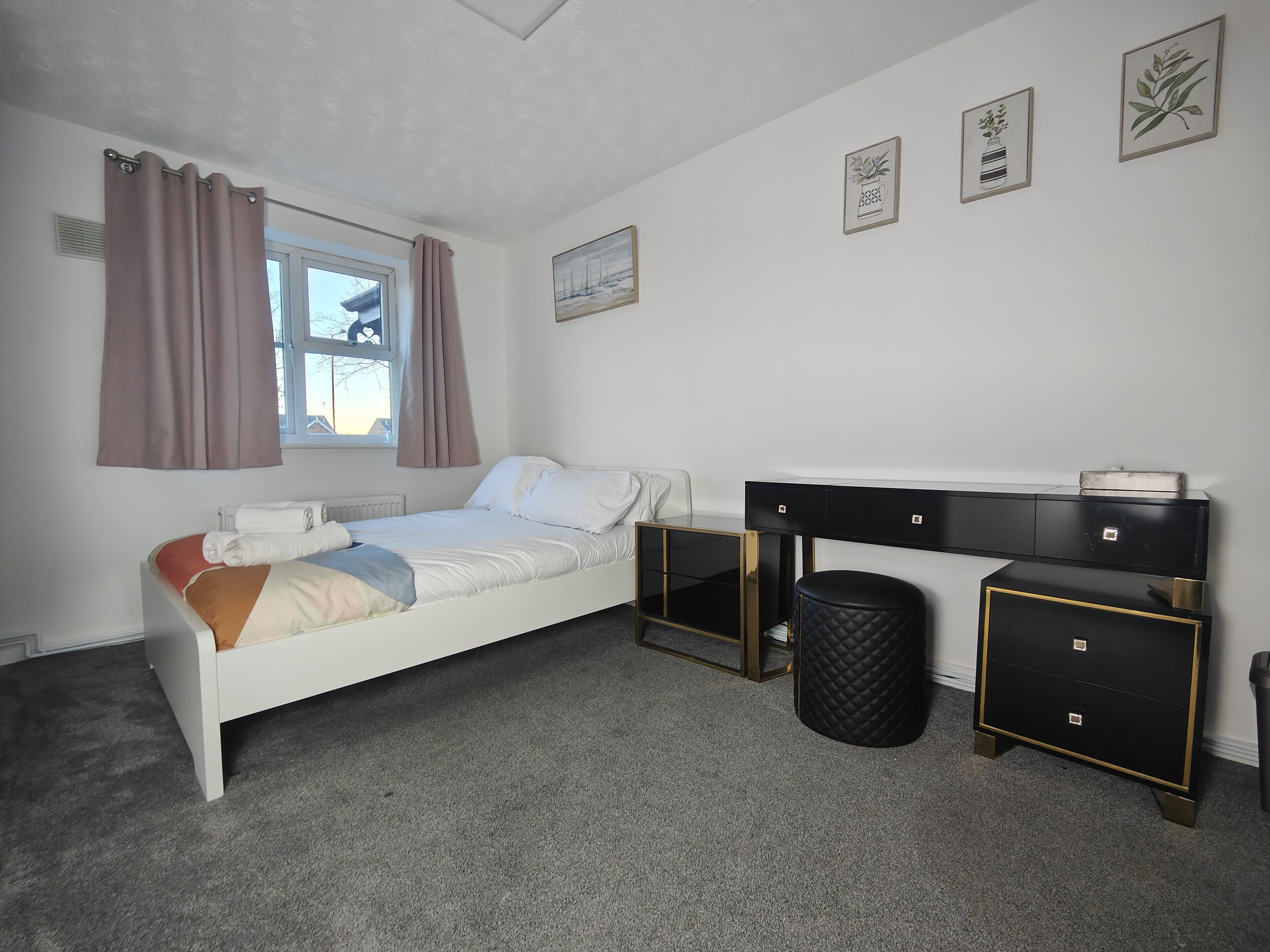 A bedroom with a bed, a desk, a chair, and a waste bin.