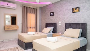 A hotel room with two beds, a large mirror, a ceiling air conditioner, and a patterned rug. - Arkan Egyptian Museum Hotel (Giza)