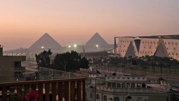 A view of the pyramids at sunset with modern buildings in the foreground. - Arkan Egyptian Museum Hotel (Giza)