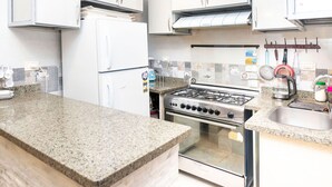 A kitchen with granite countertops, a gas stove, a refrigerator, and a sink. - Arkan Egyptian Museum Hotel (Giza)