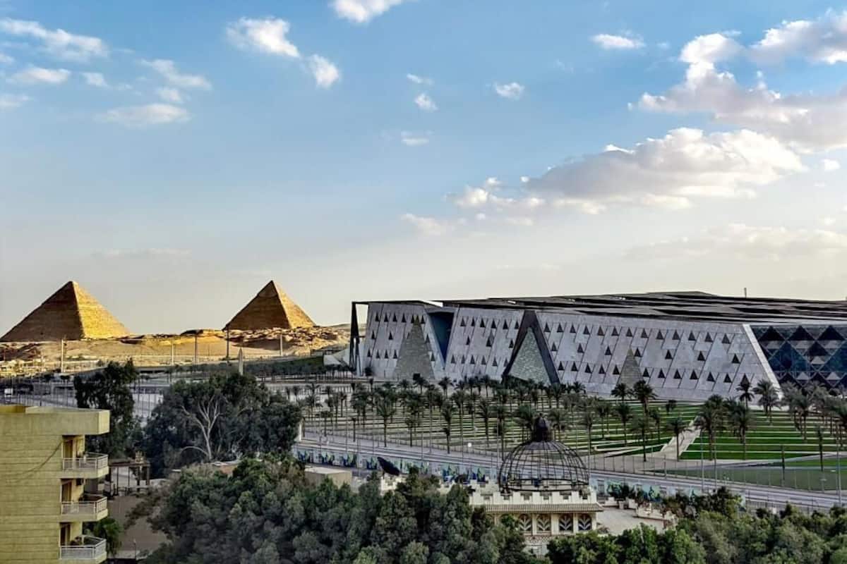 A view of the pyramids and a modern building with a geometric facade.