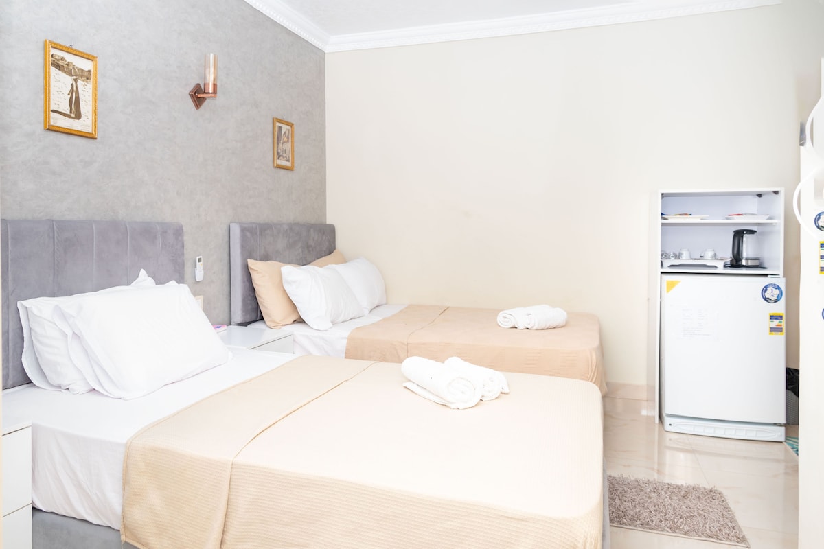 A hotel room with two beds, a refrigerator, and a coffee maker.