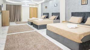 A modern hotel room with three beds, a wooden wardrobe, and a large window with curtains. - Arkan Egyptian Museum Hotel (Giza)