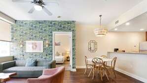 Una sala moderna con un sofá gris, un sillón rosa y un comedor con una mesa blanca y sillas de madera.