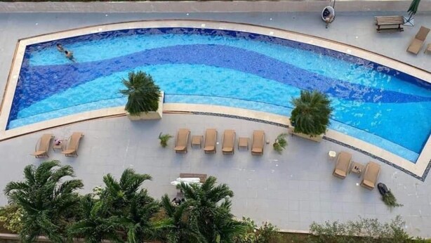 A curved swimming pool with lounge chairs and palm trees. - Saekyung Village One-Phase 2 (Lapu-Lapu City)