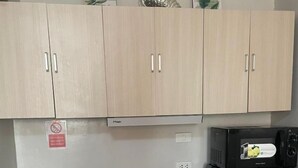 A kitchen with light wood cabinets, a stainless steel refrigerator, a microwave, a scale, a sink with a soap dispenser, and a faucet. - Saekyung Village One-Phase 2 (Lapu-Lapu City)