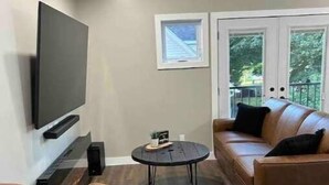 A modern living room with a flat-screen TV mounted on the wall, a round coffee table, and two leather sofas. - Gem on Prospect (Kingsville)