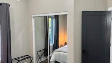 Una habitación con cama, armario y ventana con cortinas.