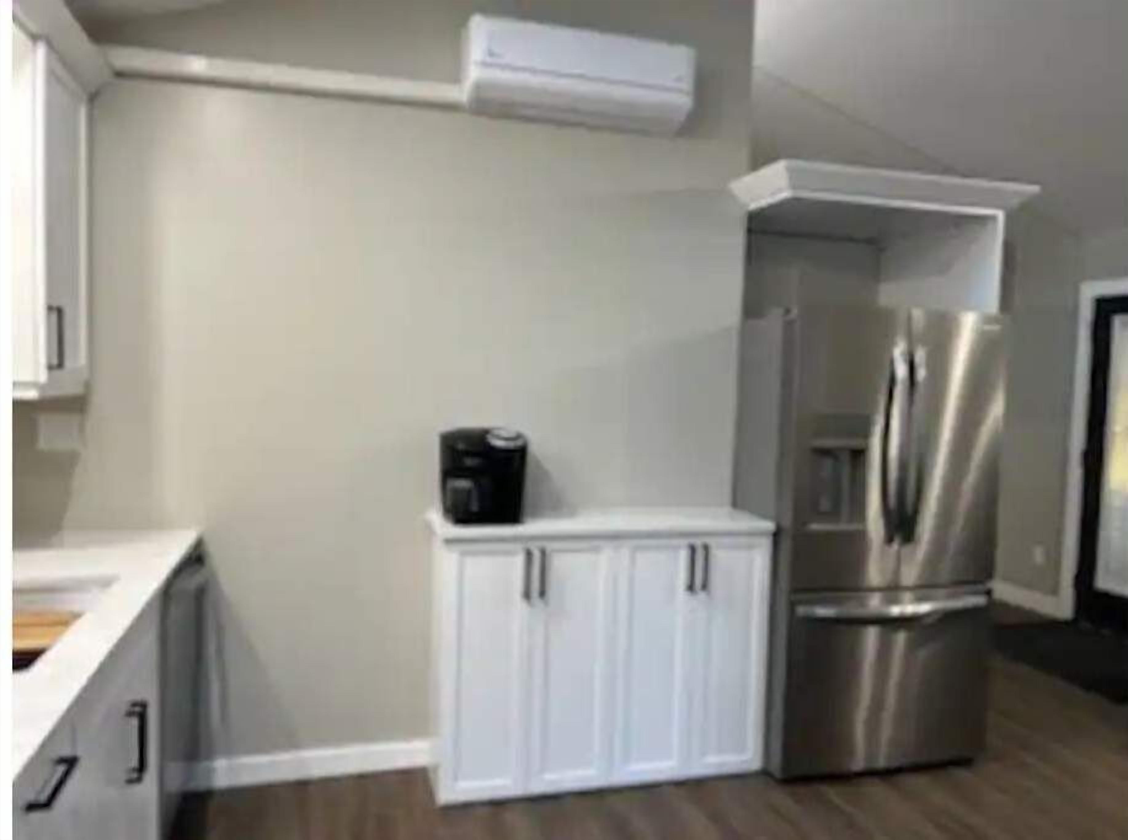 Een moderne keuken met een roestvrijstalen koelkast, witte kasten en een inbouwoven.