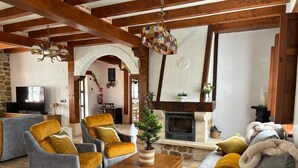 Un salon chaleureux avec une cheminée, des poutres en bois et des sièges confortables.