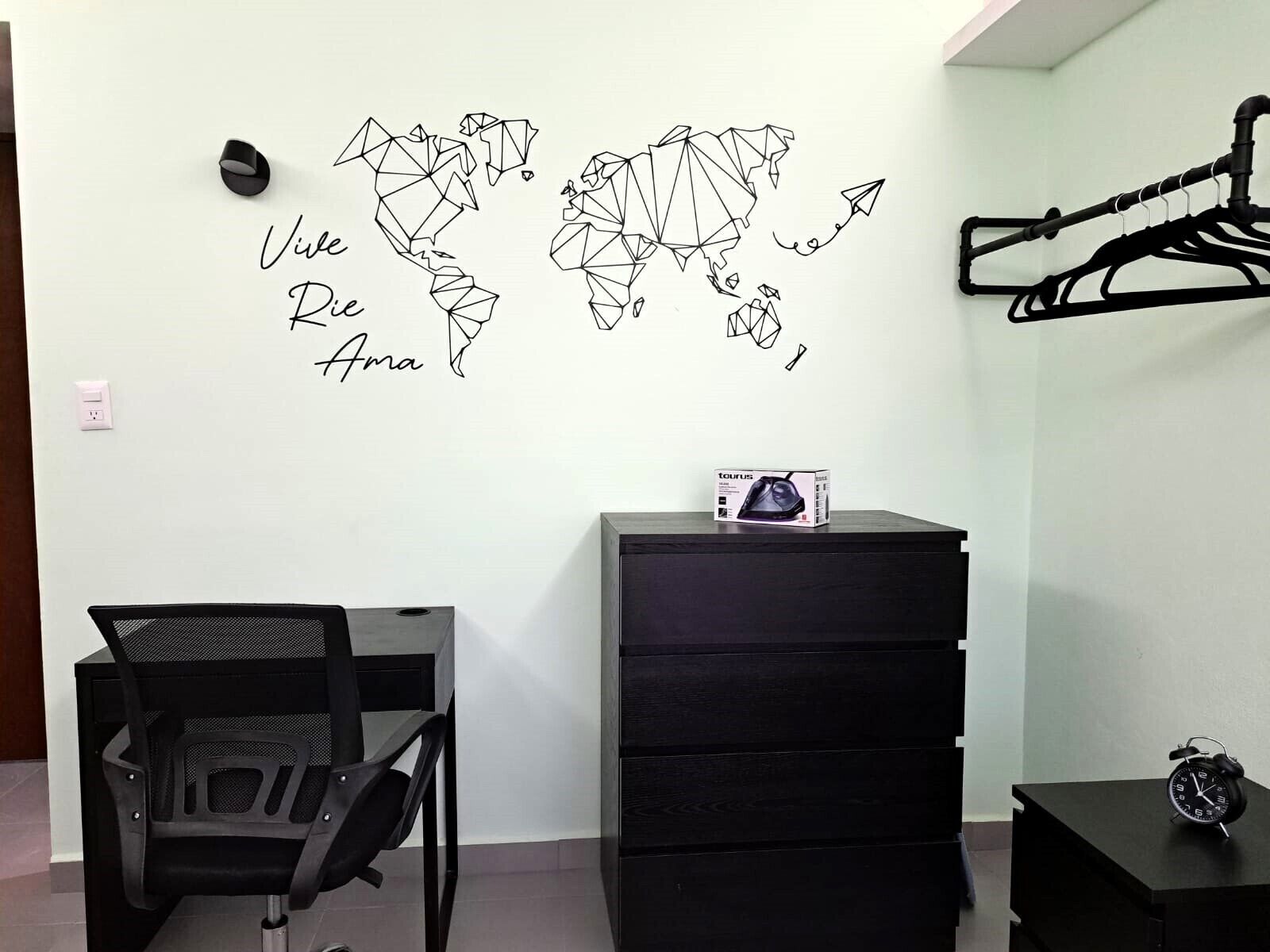 A room with a wall map, a desk, a chair, a dresser, and a clock.