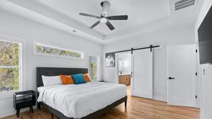 Ein Schlafzimmer mit einem Bett, einem Deckenventilator, einem Kleiderschrank und einem Fenster mit Jalousien.