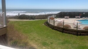 A pool area with a view of the ocean, surrounded by a wooden deck and white railings. - Paradise awaits! Beachfront condo with everything you need! (North Topsail Beach)