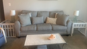 A living room with a grey sofa, two side tables with lamps, a coffee table, and a framed sign on the wall. - Paradise awaits! Beachfront condo with everything you need! (North Topsail Beach)