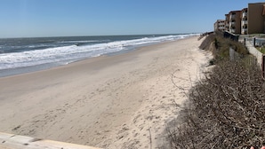 A beach with a sandy shore, waves, and a building with balconies. - Paradise awaits! Beachfront condo with everything you need! (North Topsail Beach)
