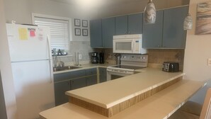 A modern kitchen with a central island, a microwave, stove, and a toaster. - Paradise awaits! Beachfront condo with everything you need! (North Topsail Beach)