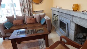 Ein Wohnzimmer mit einer Couch, einem Glastisch, einem Kamin und einem Steinvorsatz.