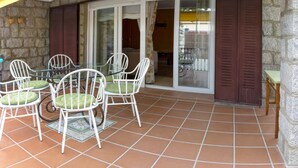 Eine Terrasse mit Glastür zu einem Raum, umgeben von Steinmauern und einem gefliesten Boden.