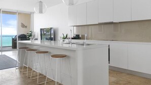Une cuisine moderne dotée d’un îlot central, de tabourets de bar et de luminaires suspendus.