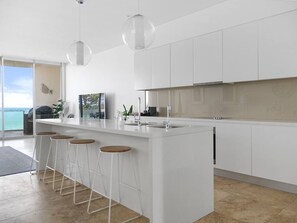 A modern kitchen with a central island, bar stools, and pendant lighting.
