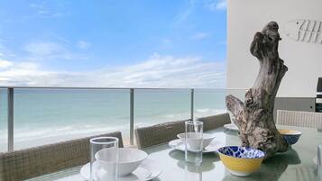 Enjoy ocean views from this dining area with a glass table and wicker furniture.