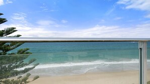 Une vue sur la plage depuis un balcon, avec un ciel dégagé et une mer calme.