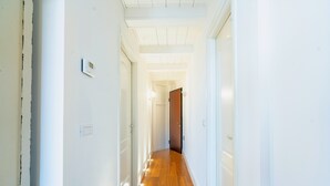 Ein Korridor mit Holzboden, weißen Wänden und einer Tür am Ende.
