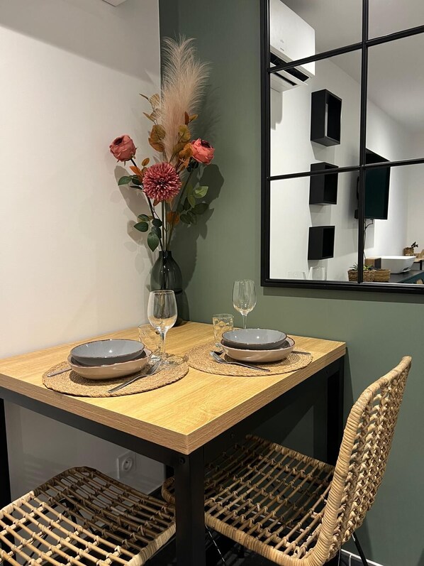 A dining table with two plates, a vase with flowers, and a chair.