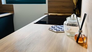 Una cocina moderna con encimera de madera, un tarro de vidrio con una pajita negra y una ventana con vistas al cielo.