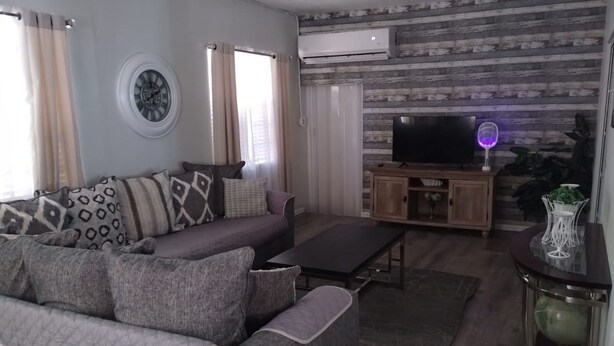 A living room with a grey sofa, a coffee table, a TV on a wooden cabinet, and a decorative globe on a side table.