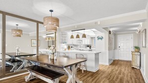 Una cocina amplia con armarios blancos, una isla central e iluminación colgante.