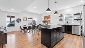 A modern kitchen with black cabinetry, stainless steel appliances, and pendant lighting.