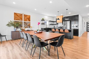 A modern kitchen with black cabinets, stainless steel appliances, and a wooden dining table with black chairs.
