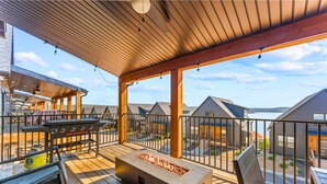 A covered outdoor patio with a grill, seating, and a fire pit.
