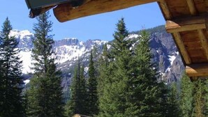 Eine Blockhütte mit Blick auf schneebedeckte Berge und dichten Wald.