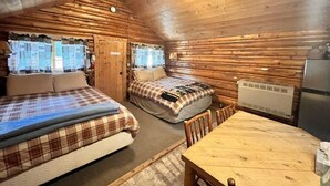 Een houten blokhutkamer met twee bedden, een houten tafel en een plafondventilator.