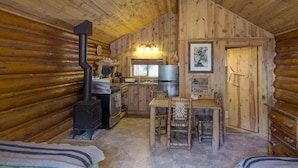 L’intérieur d’une cabane en rondins comprend une cuisine, un coin repas et deux lits.