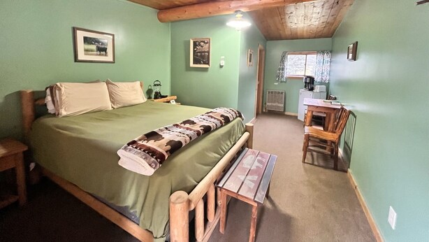 A cozy room with a bed, a small table, and a kitchenette area. - Newly Remodeled Motel Room with 1 Queen Bed, Bathroom with shower. Mini Fridge, Coffee Maker. Situated close to the General Store in Silver Gate, MT (SILVER GATE)