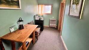 A cozy room with a wooden table, benches, a kettle, and a radiator.