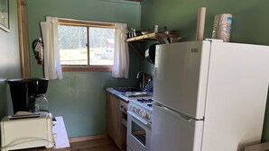 Una cocina compacta con refrigerador, estufa y cafetera.