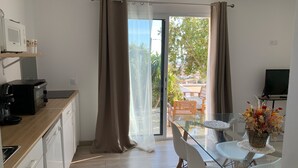 A modern kitchen with a microwave, coffee maker, and a glass dining table with chairs. - Charmant T2 vue mer (Bastia)